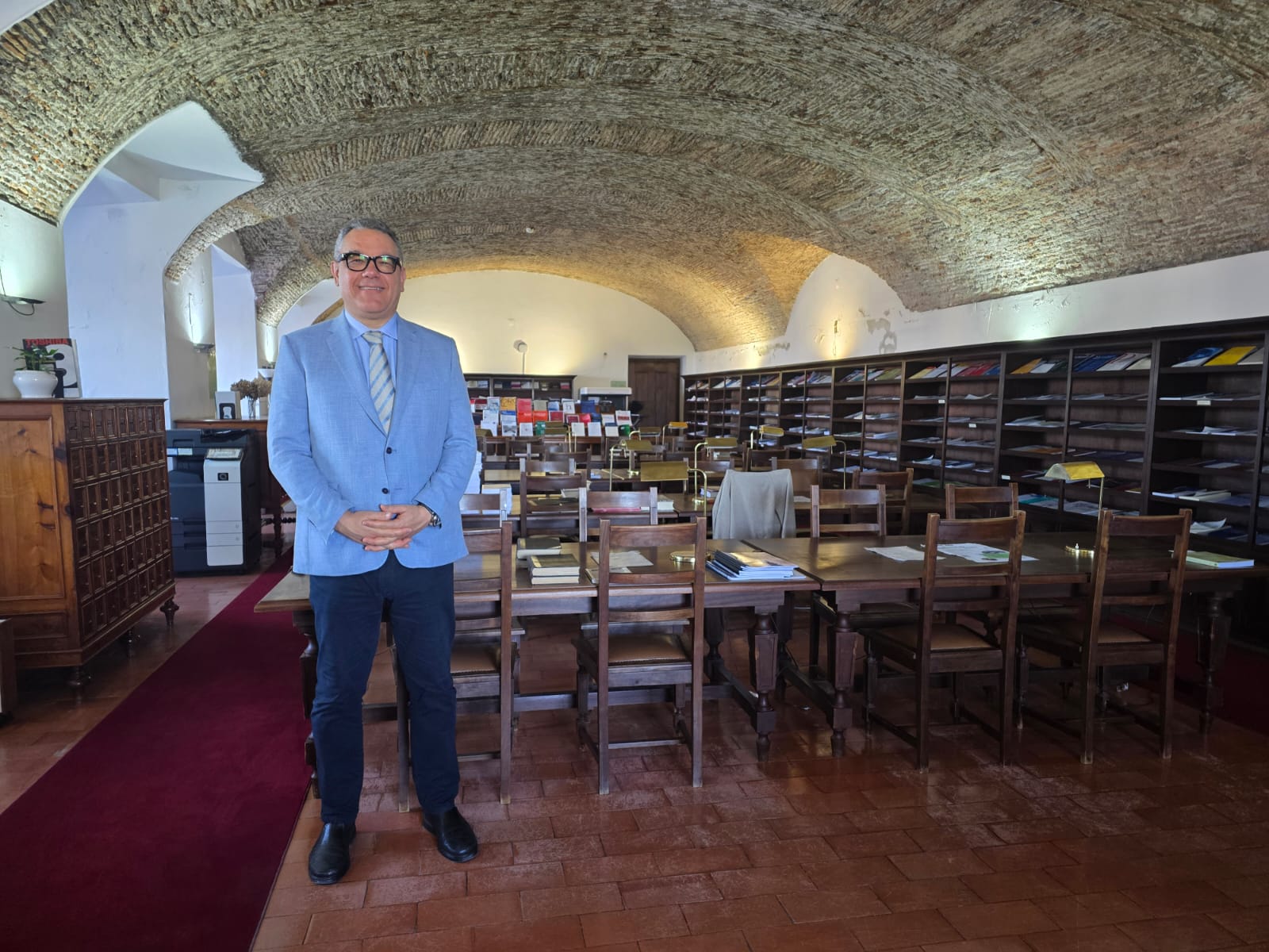 Dr. Cláudio Henrique de Castro em pé na sala de leitura de biblioteca histórica